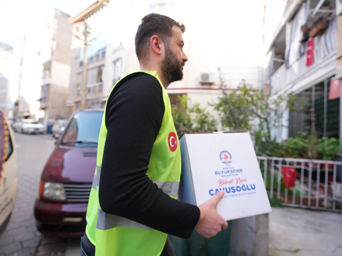 Yelekli görevli sokakta elinde Denizli Büyükşehir Belediyesi yazılı gıda kolisi taşıyor