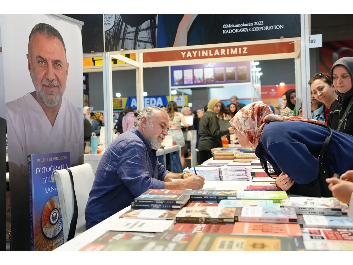 Denizli TUYAP Kitap Fuarinda bir yazar okuyucusunun kitabini imzaliyor.