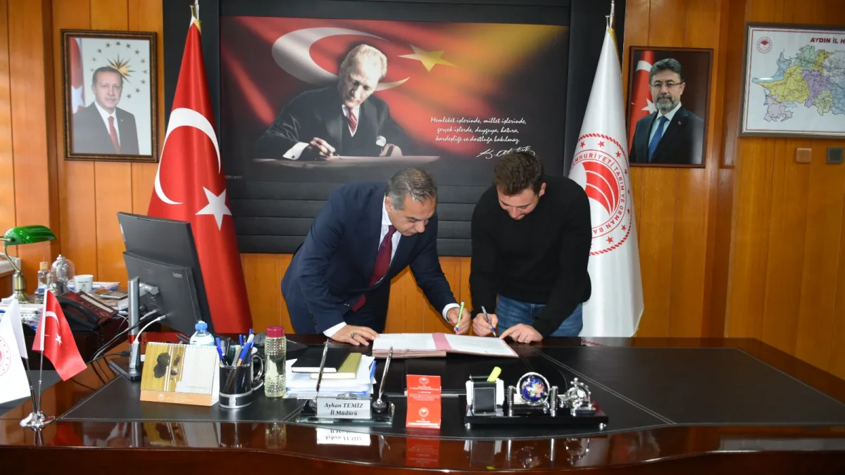 Makam masasında evrak imzalayan iki kişi.