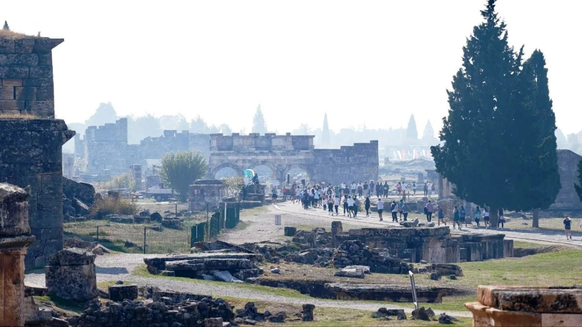 Tarihi kalıntılar arasındaki yolda yürüyen ve koşan insanlar