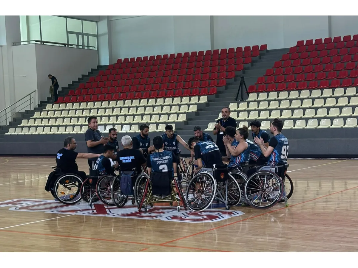 Kapalı spor salonunda tekerlekli sandalyeli sporcular sahada toplanmış bulunuyor.