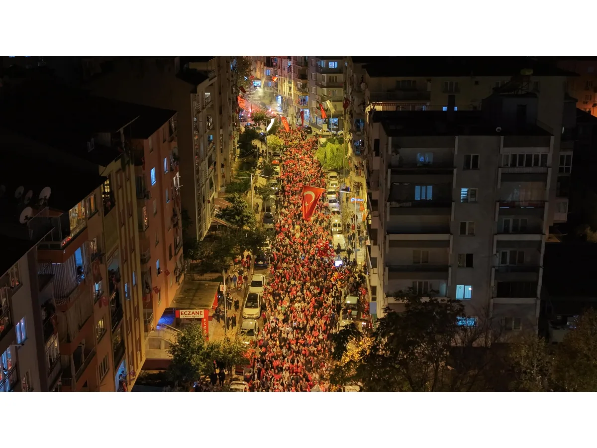 Gecenin karanlığında binalar arasındaki caddede Türk bayraklarıyla yürüyen kalabalık