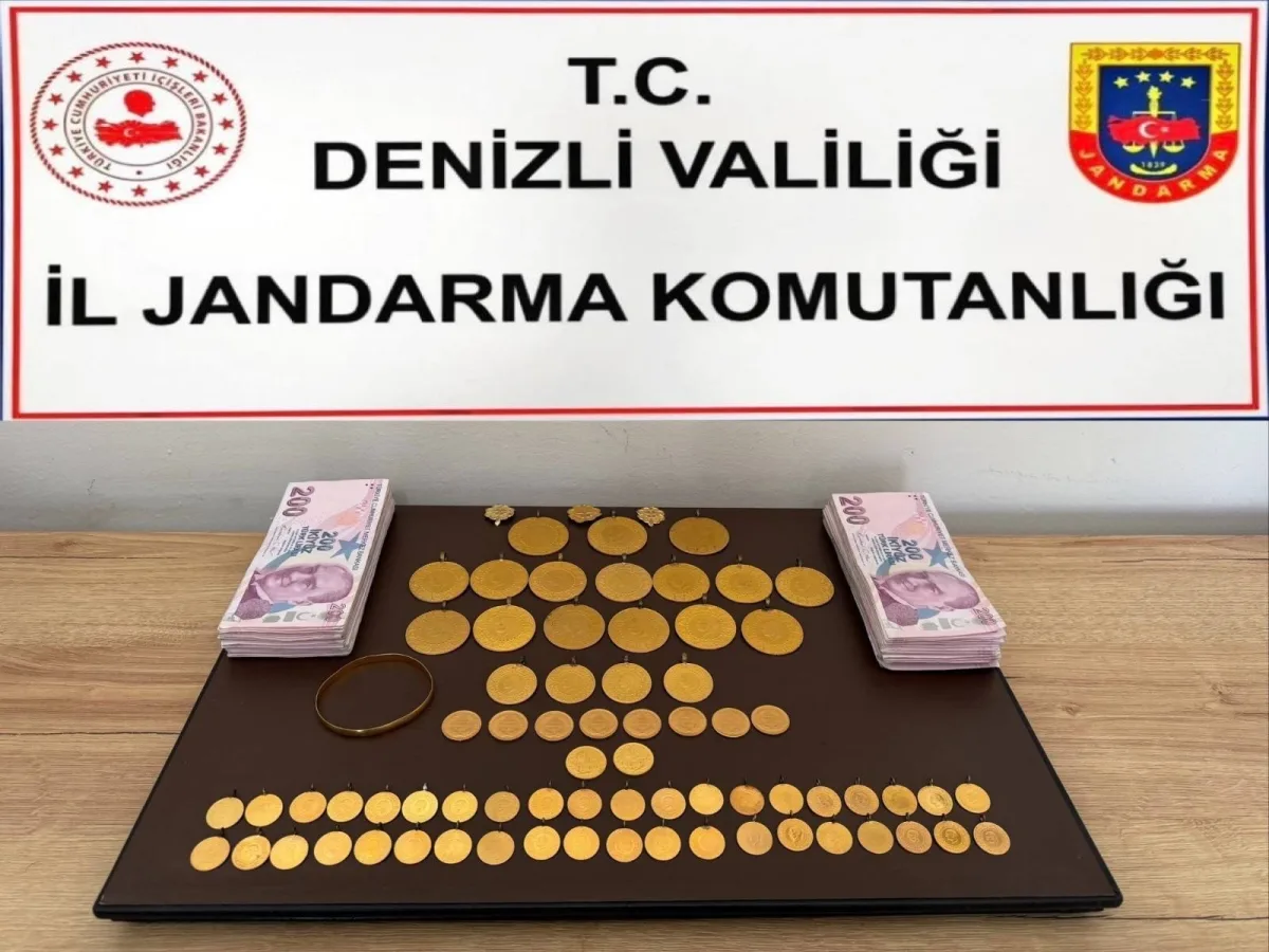 Masa üzerinde sergilenen altınlar ve kağıt paralar ile arka planda Denizli Valiliği İl Jandarma Komutanlığı tabelası yer alıy