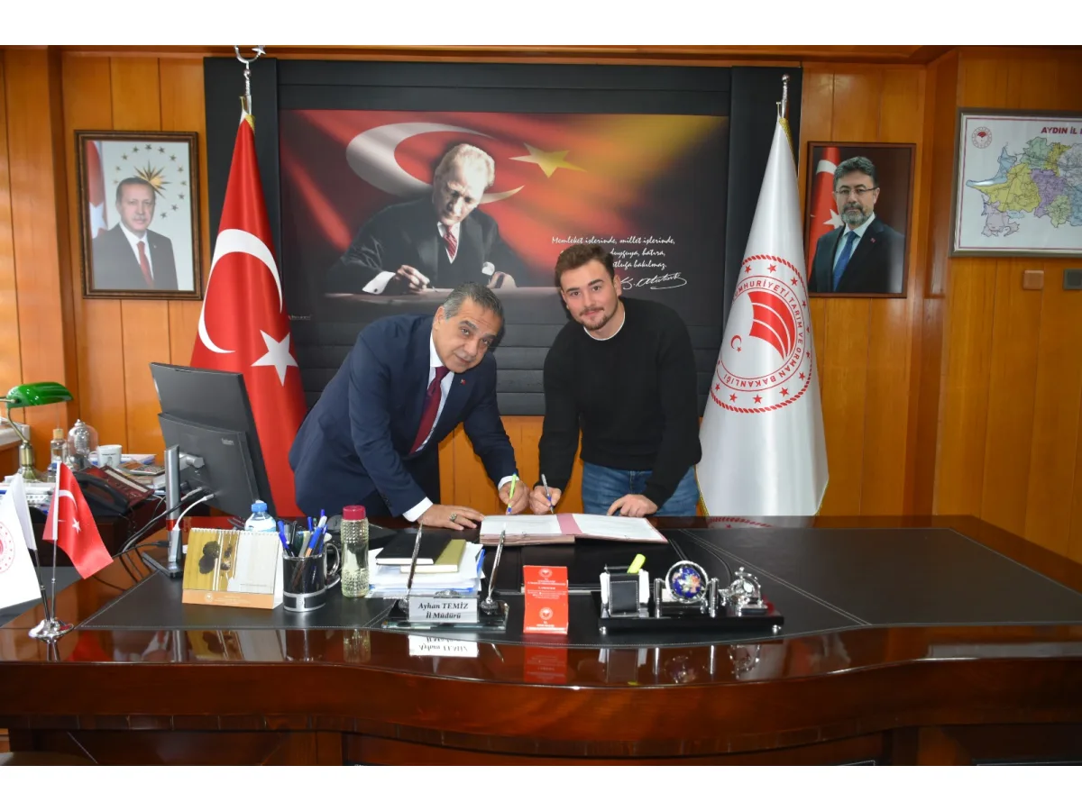 Makam masasında evrak imzalayan iki kişi.