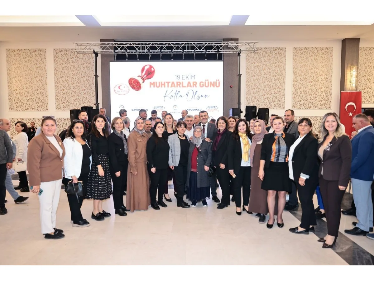 Toplantı salonunda bir araya gelen muhtarlar ve yöneticiler toplu halde poz veriyor
