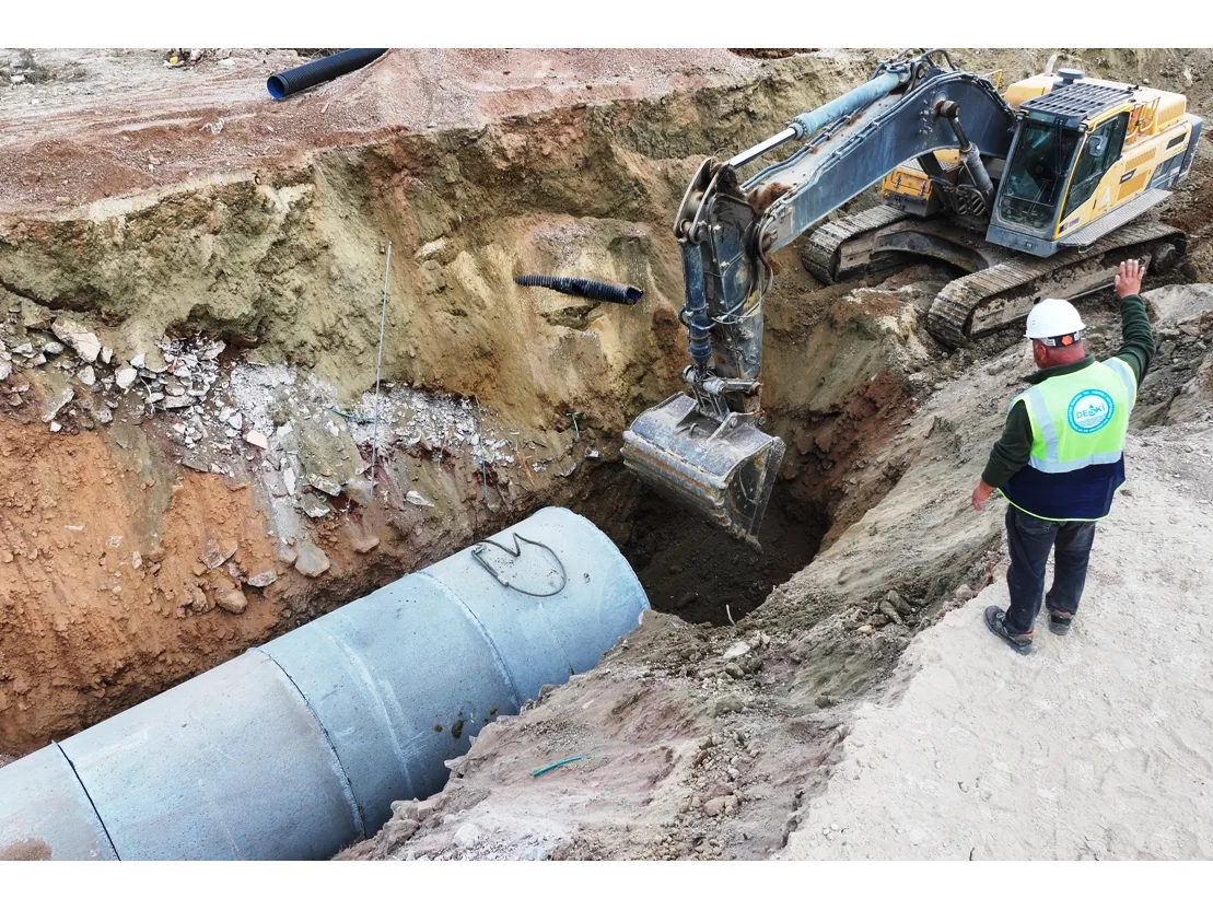 Kazı alanında çalışan işçi ve iş makinesi